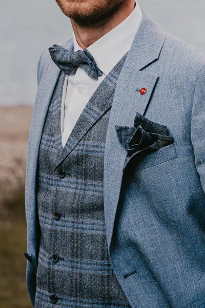 Nahaufnahme von Weste und Sakko mit Fliege und Einsteckttuch aus blauem Leinen auf der Bergsee-Hochzeit